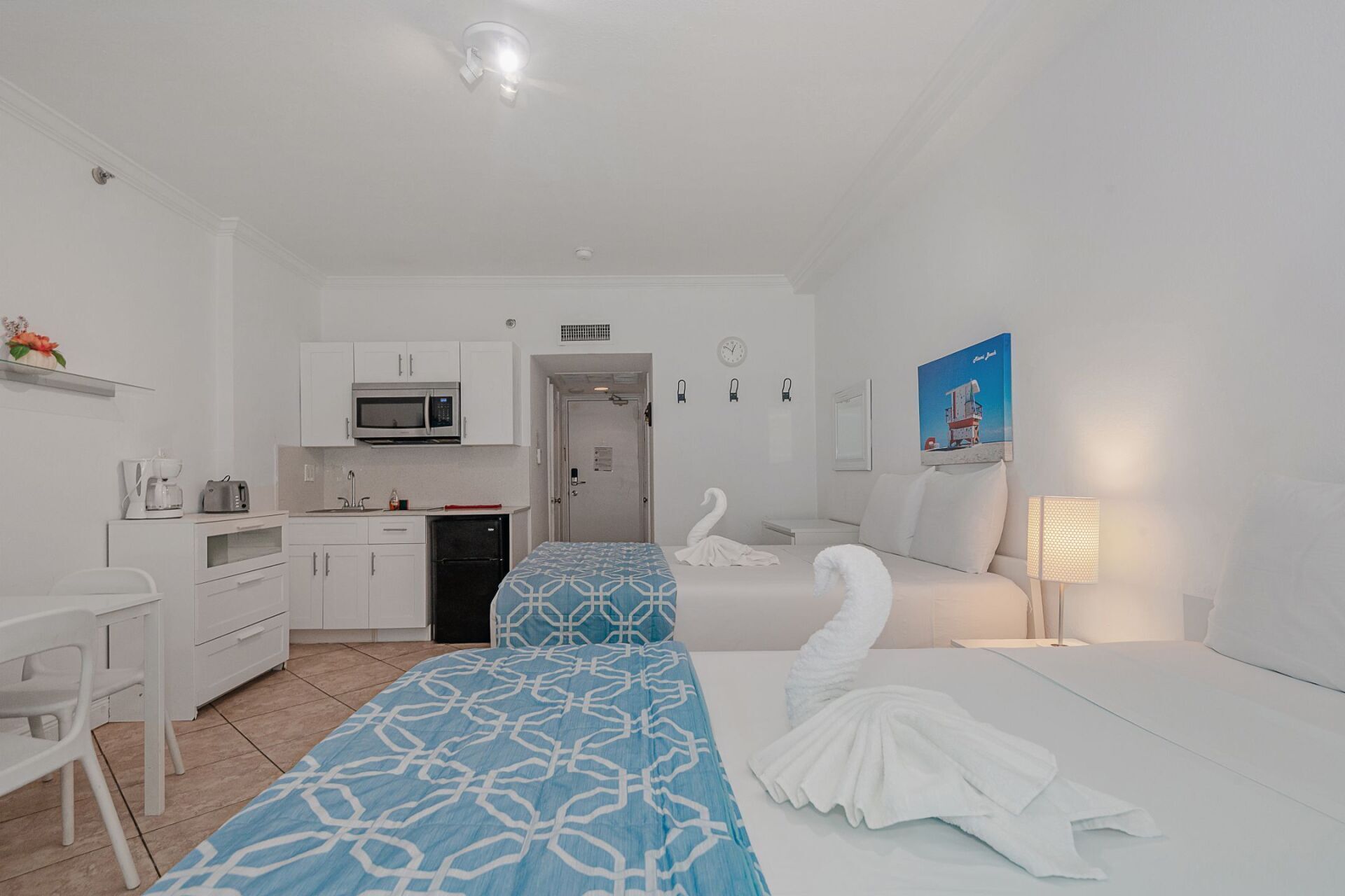 A hotel room with two beds and a kitchen.