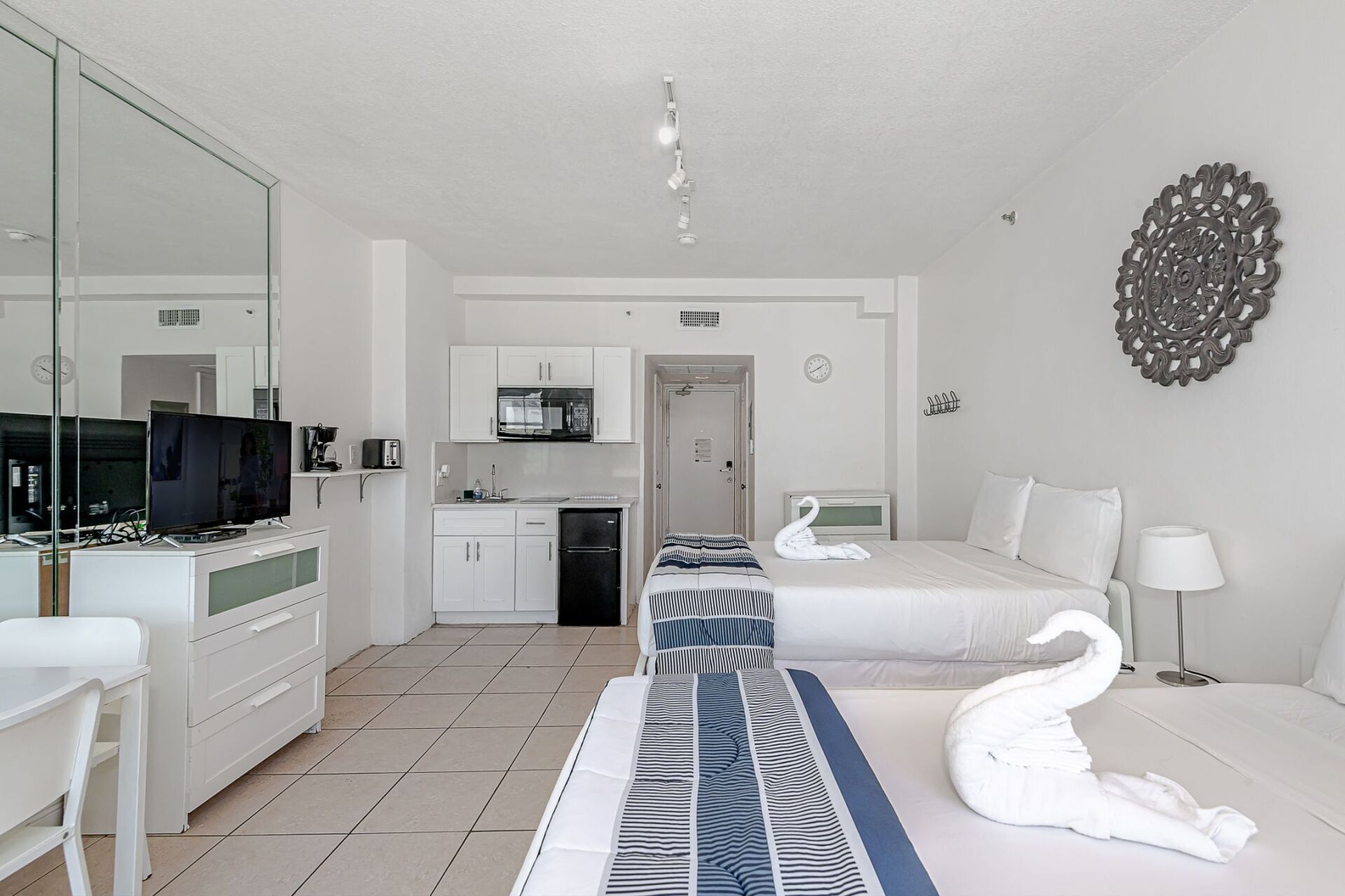 A hotel room with two beds , a desk , and a television.