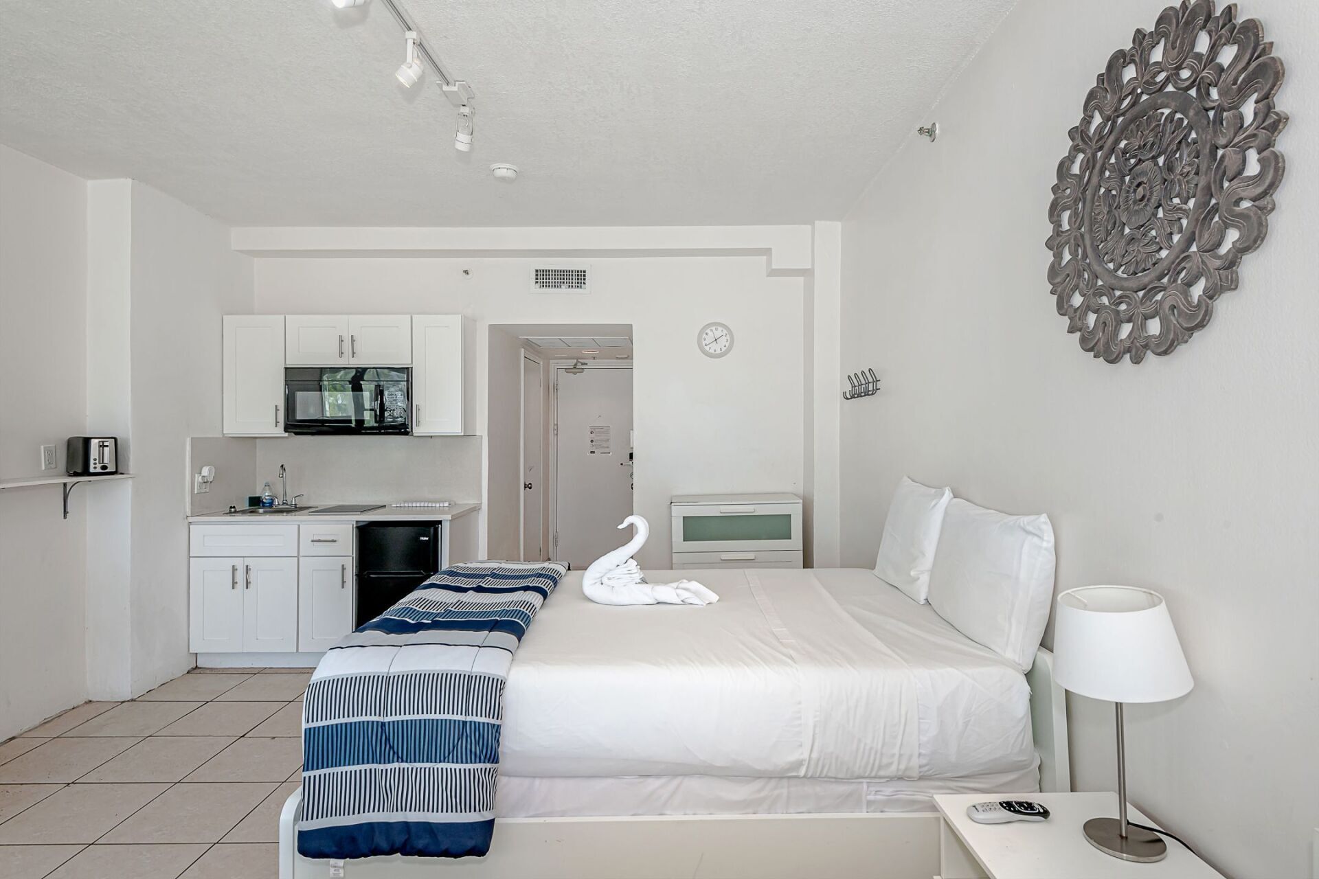 A hotel room with a large bed and a kitchen