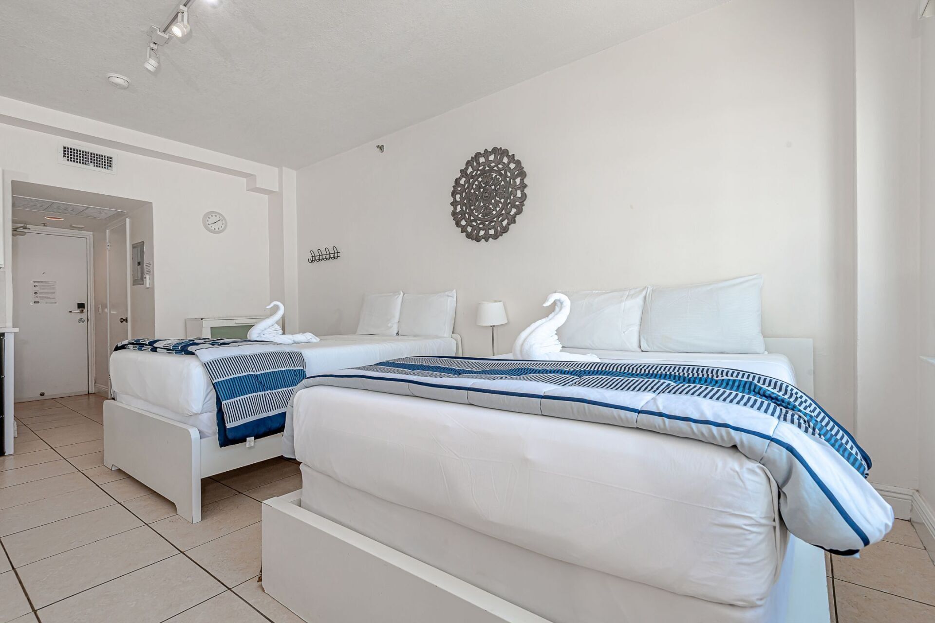 A hotel room with two beds and a clock on the wall.
