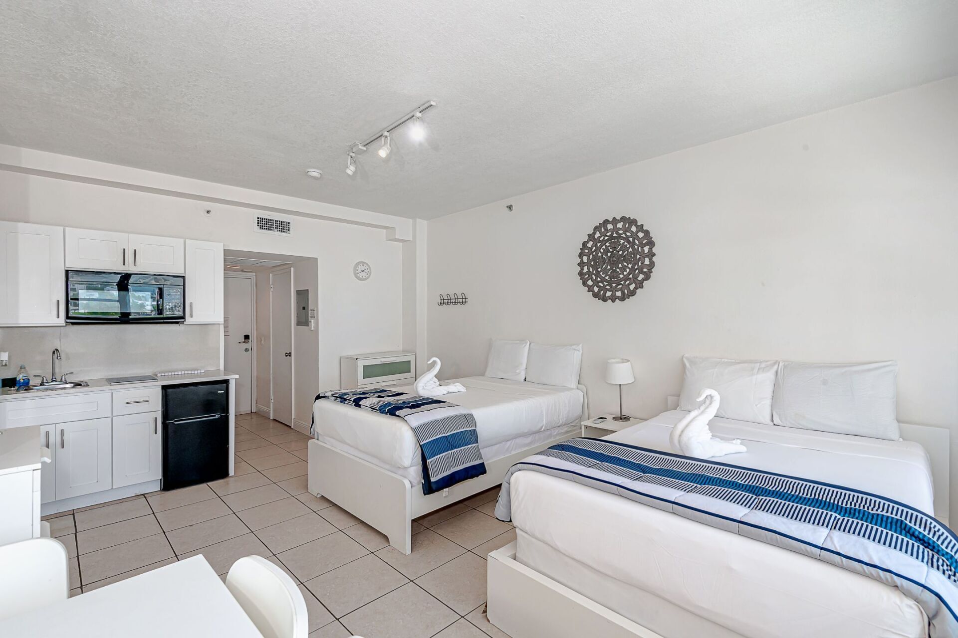 A hotel room with two beds and a kitchen.