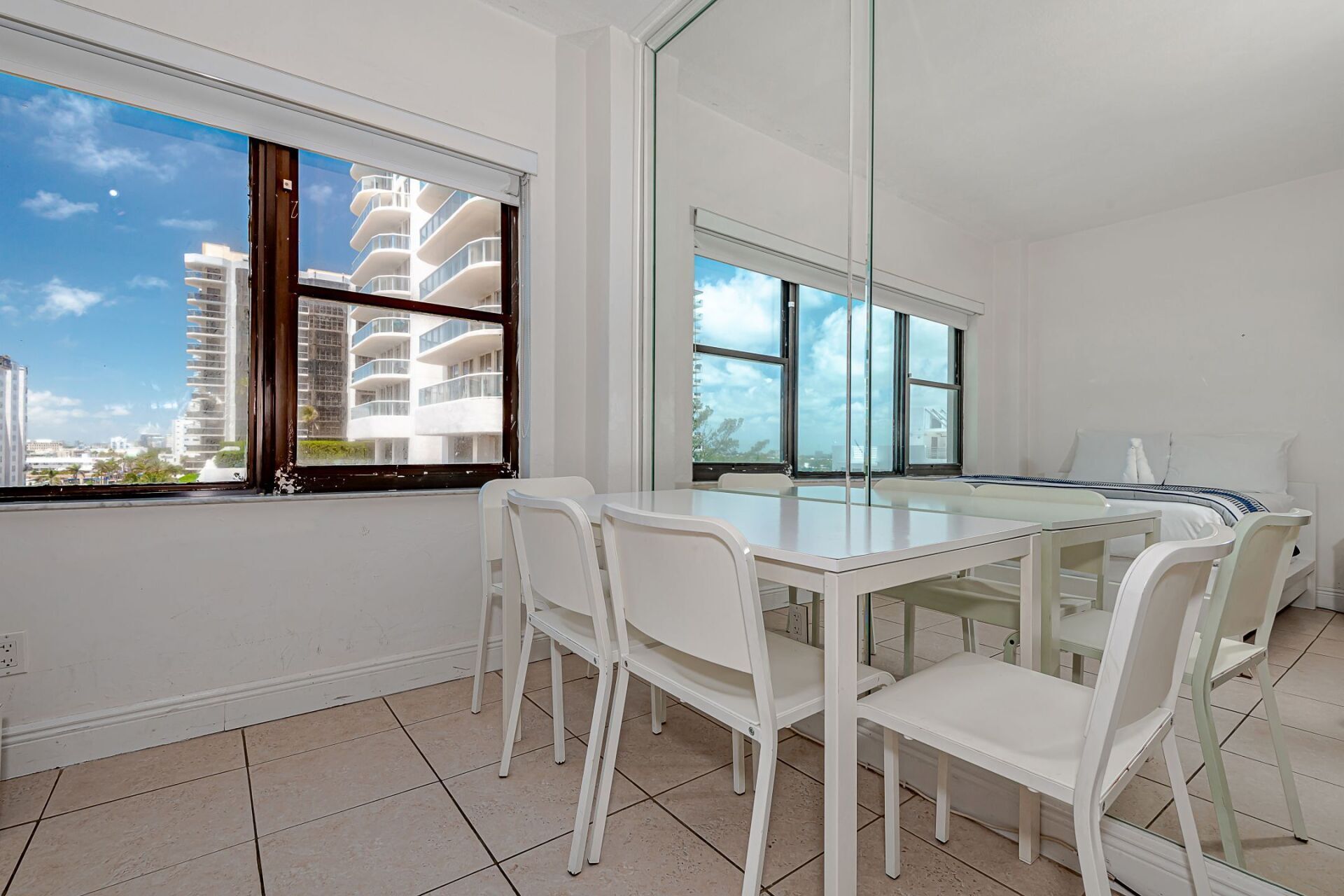 A dining room with a table and chairs and a large mirror.