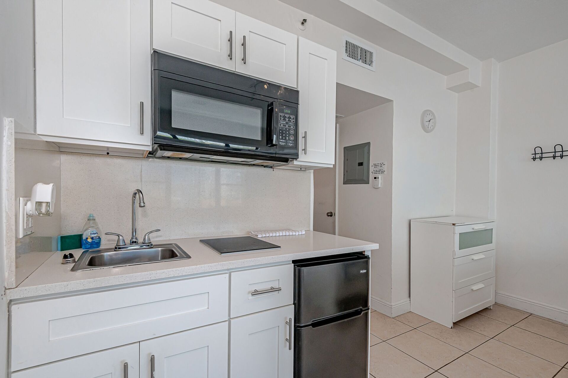 A kitchen with white cabinets , a sink , a microwave , and a dishwasher.