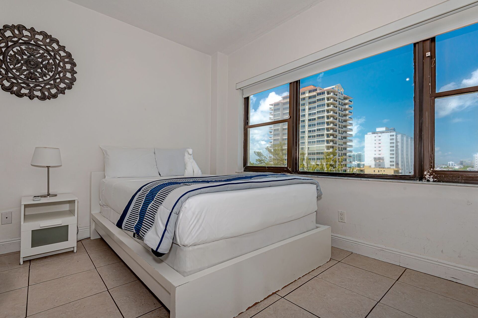 A bedroom with a bed and a window with a view of a city.