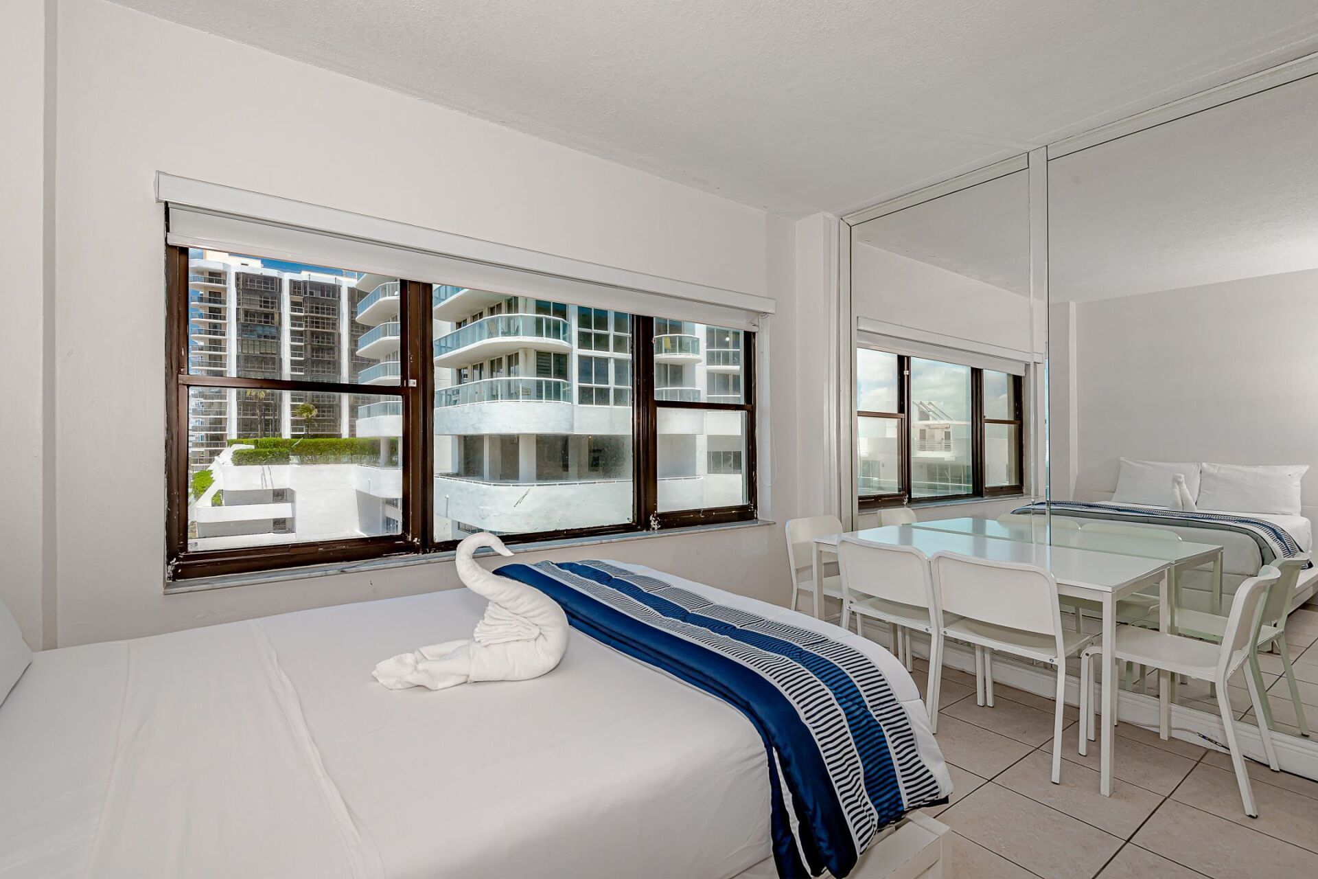 A hotel room with a bed , dining table and chairs.