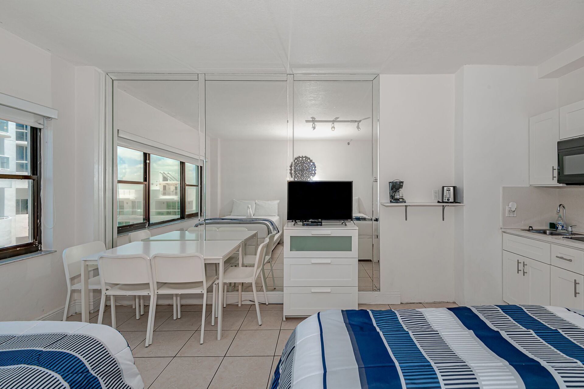 A hotel room with two beds , a dining table , chairs and a television.