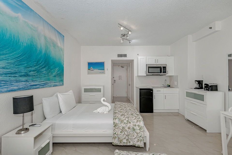 A hotel room with a large bed and a kitchen