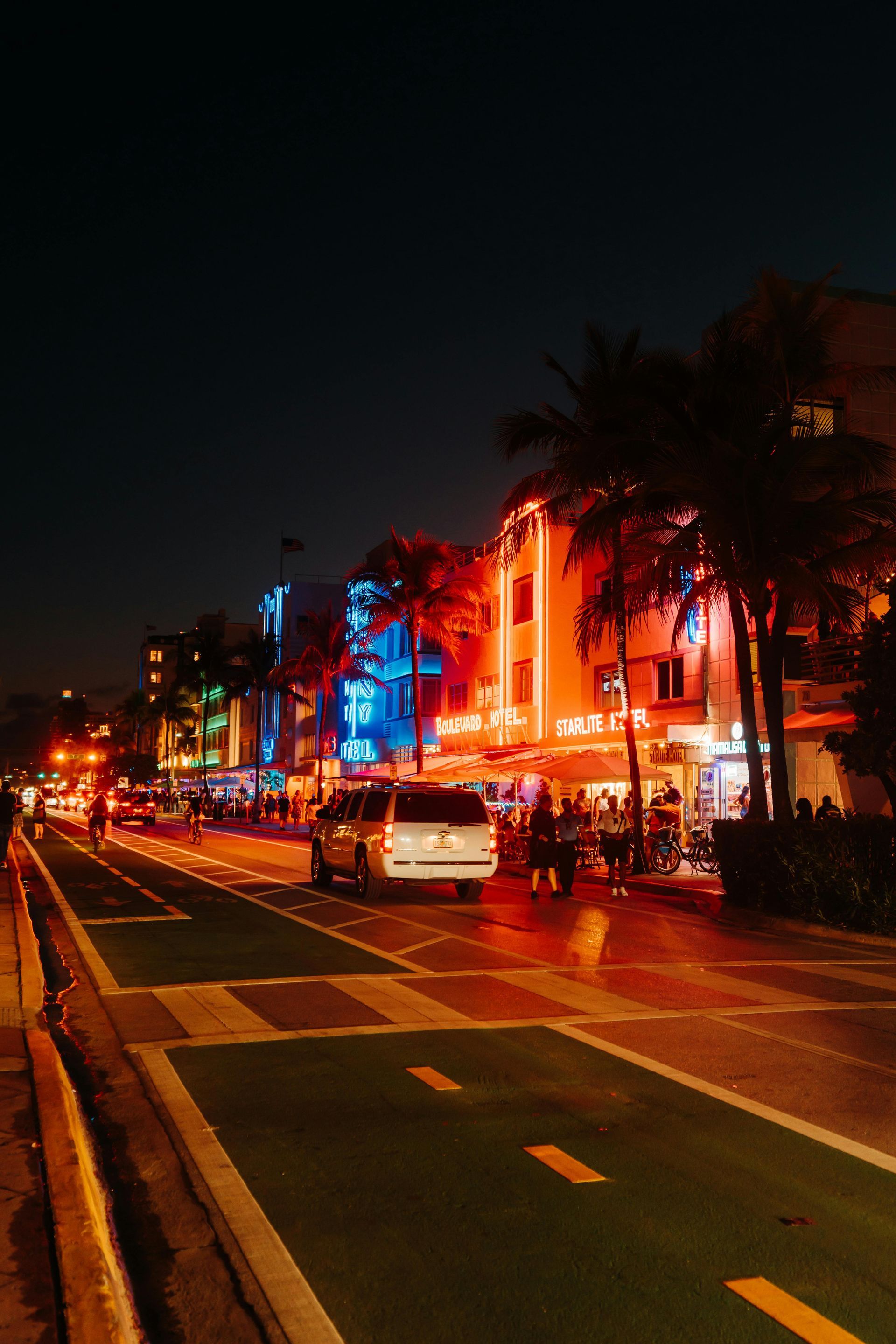 A city street at night with a lot of lights on the buildings.