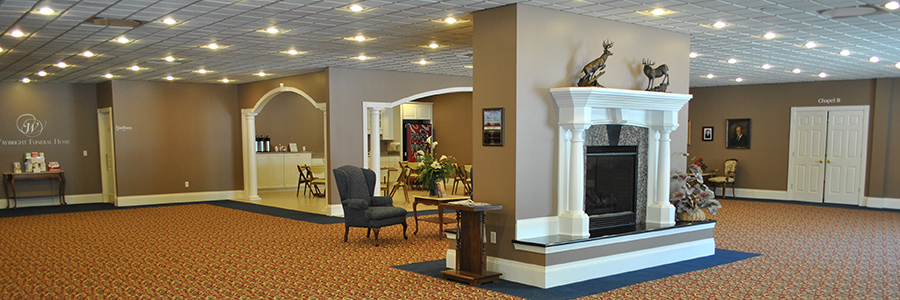 Interior of a formal room, likely a reception hall. Features a fireplace, chairs, and a patterned carpet.