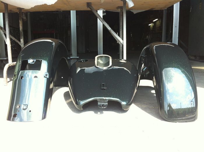 Un réservoir de moto et des garde-boue sont posés sur une table