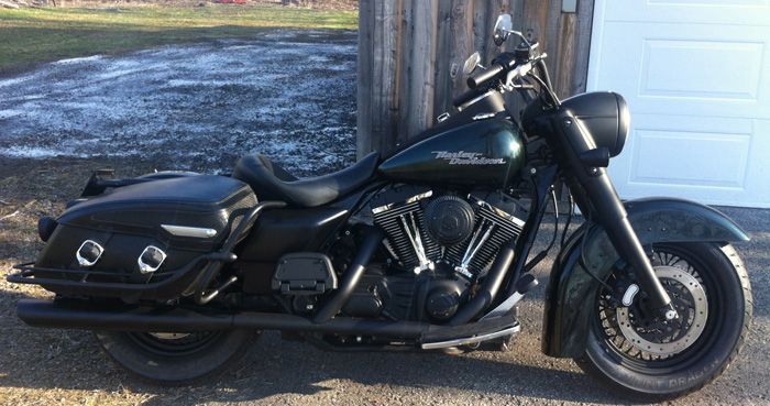 Une moto Harley Davidson noire est garée devant une porte de garage.