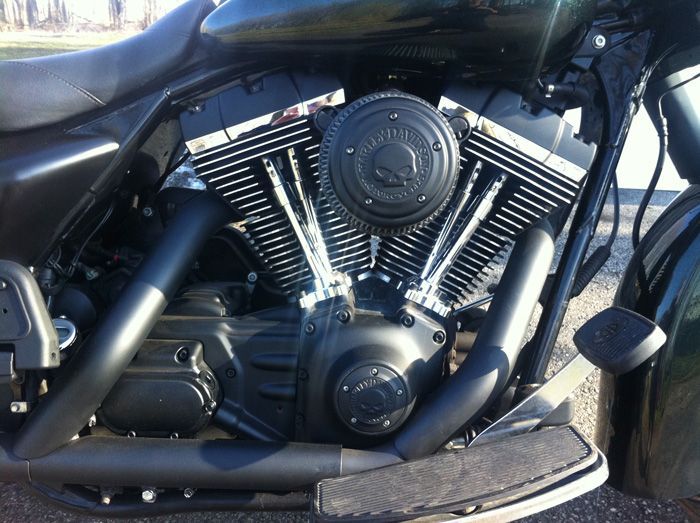 Une moto Harley Davidson noire est garée sur le bord de la route