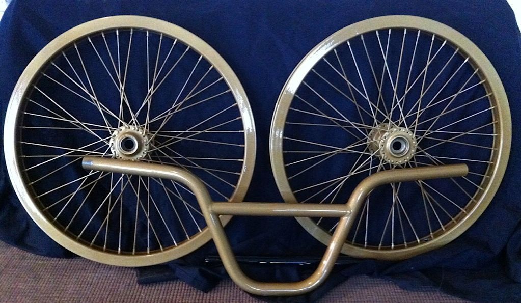 A pair of gold bicycle wheels and handlebars on a blue cloth
