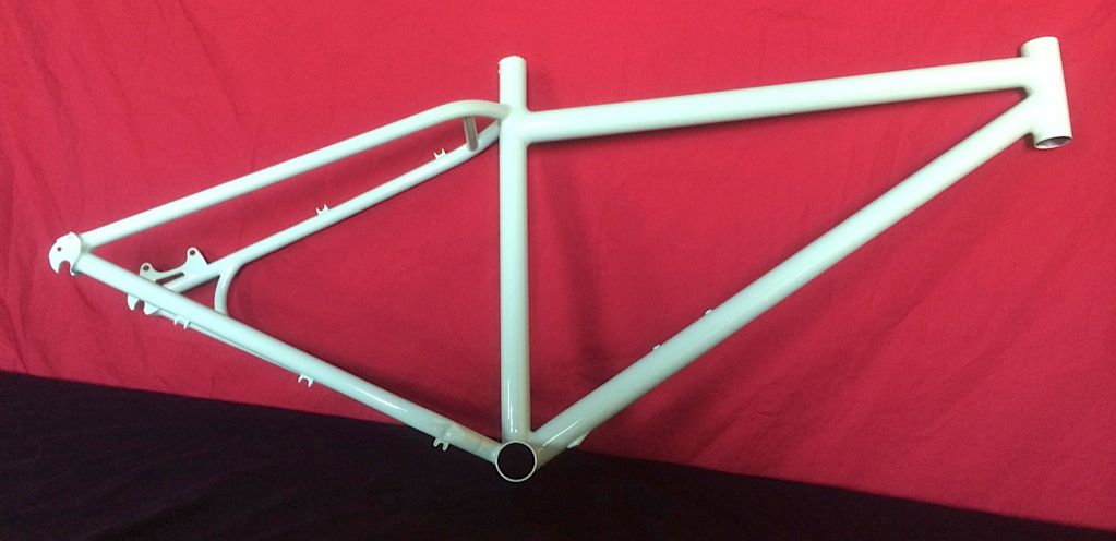 Un cadre de vélo blanc est posé sur un tissu rouge