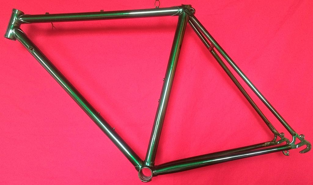 A green bicycle frame is sitting on a red cloth