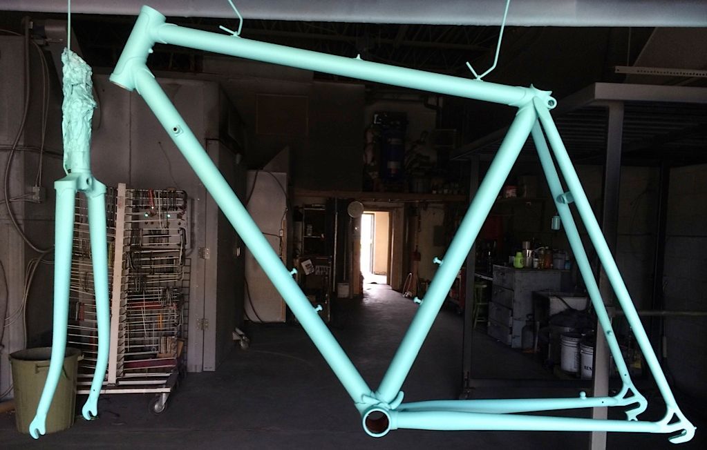 Un cadre de vélo est peint en bleu clair dans un entrepôt