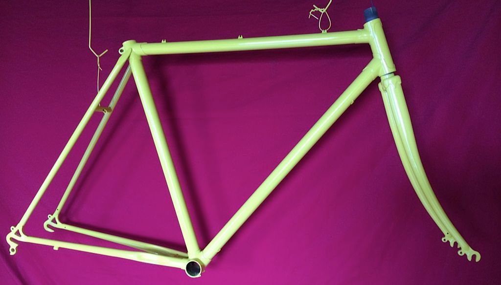 Un cadre de vélo jaune est accroché à un mur violet