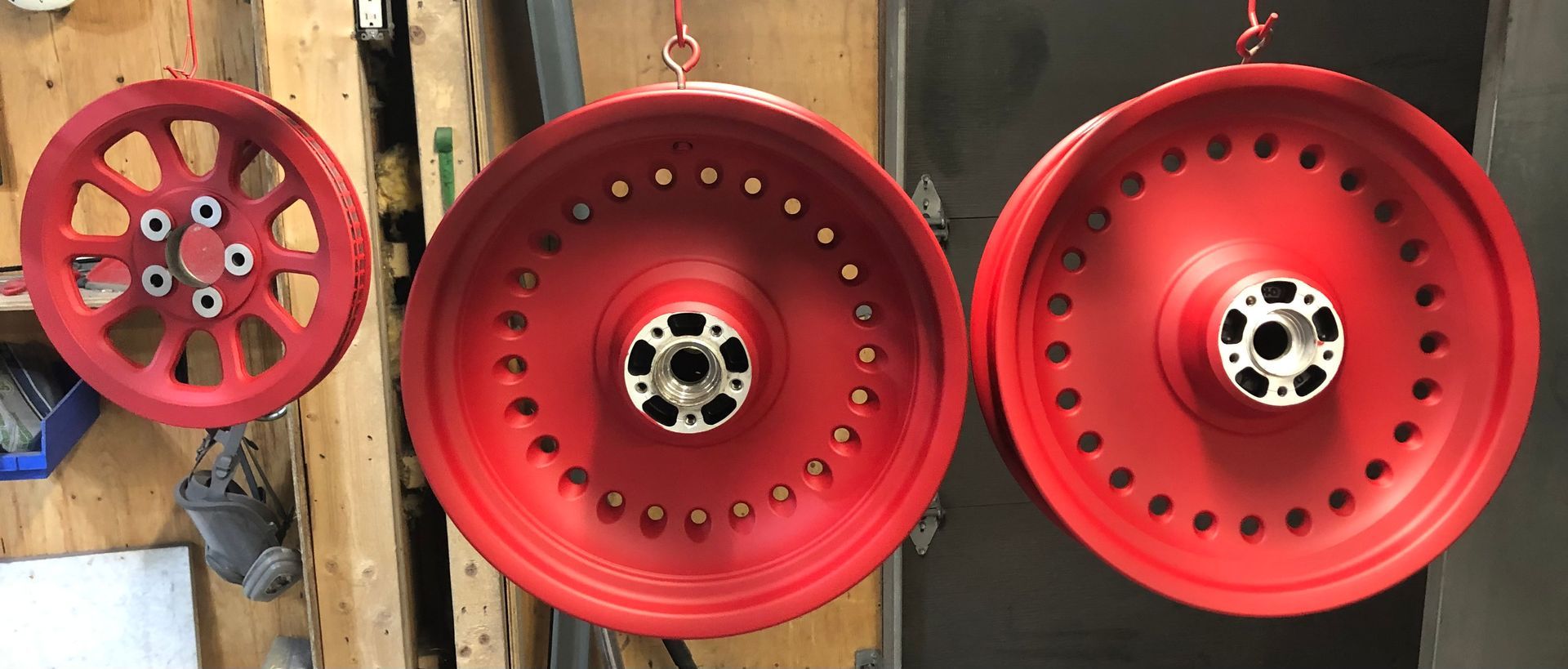 Three red wheels are hanging on a wooden wall.