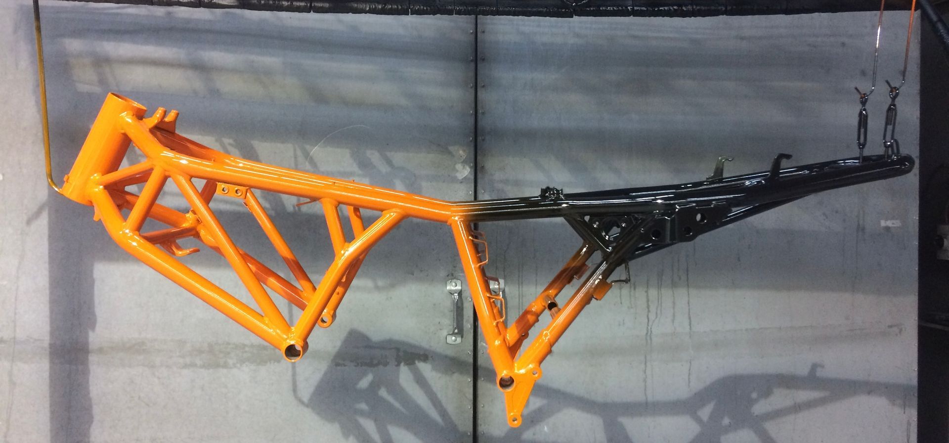 Une photo d'un cadre de moto peint en orange et noir