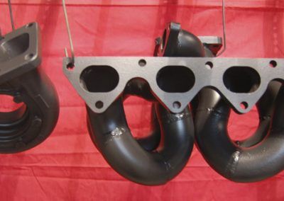 Un collecteur d'échappement noir est suspendu à un tissu rouge.