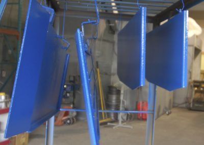 Un tas de pièces métalliques bleues suspendues à un support dans une pièce.