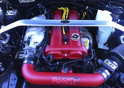 Un gros plan d'un moteur de voiture avec un tuyau rouge sur lequel est écrit Rocket Bunny