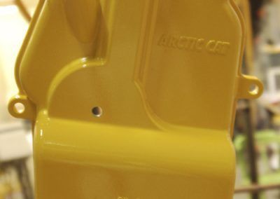 Un capot de moteur Arctic Cat jaune est posé sur une table.