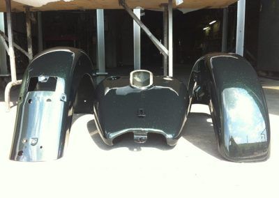 Un réservoir de moto et des garde-boue sont posés sur une table.