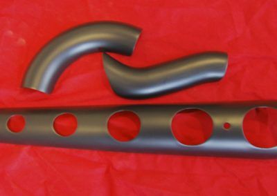 Un tuyau en métal avec des trous est posé sur un tissu rouge