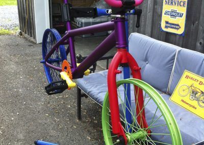 Un vélo violet est assis sur un banc à côté d'un panneau de service