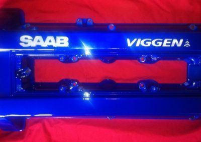 Un capot moteur Saab bleu repose sur un tissu rouge