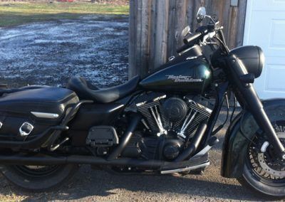 Une moto Harley Davidson noire est garée devant une porte de garage.