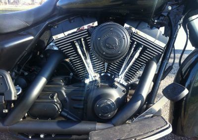Une moto Harley Davidson noire est garée sur le bord de la route