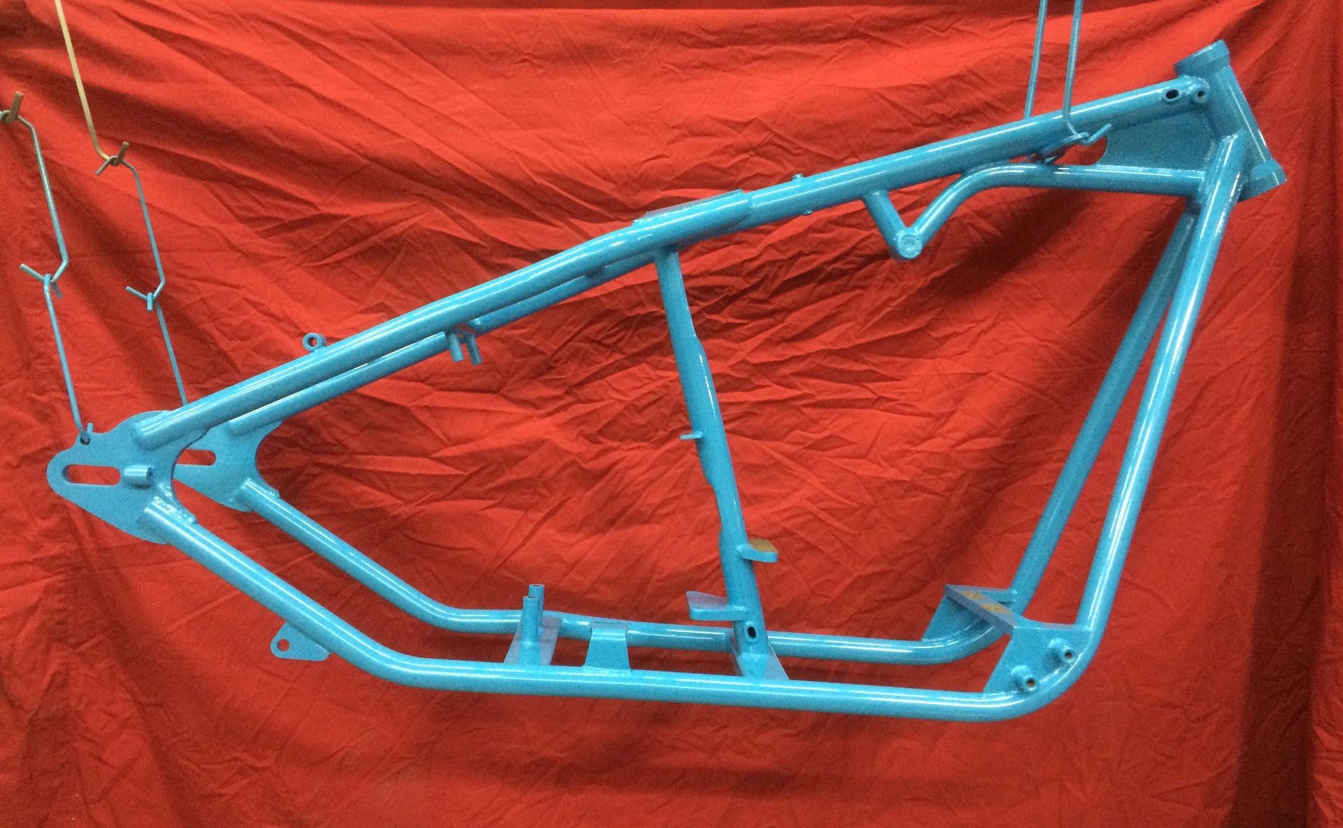 Un cadre de moto bleu est accroché à un tissu rouge