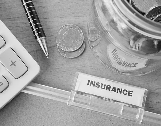 A jar of coins and a calculator on a table with a label that says insurance