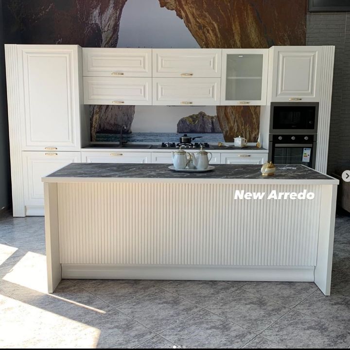 Una cucina con mobili bianchi e una grande isola al centro.