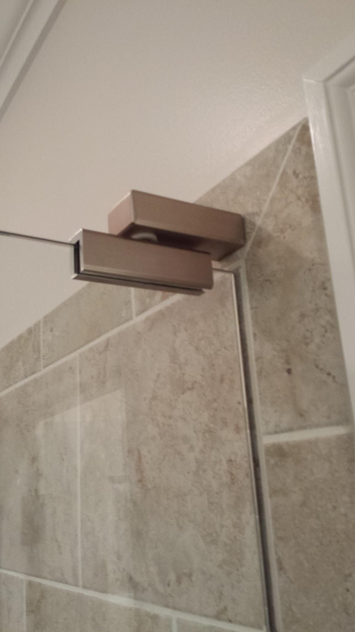 A close up of a door hinge on a tiled wall