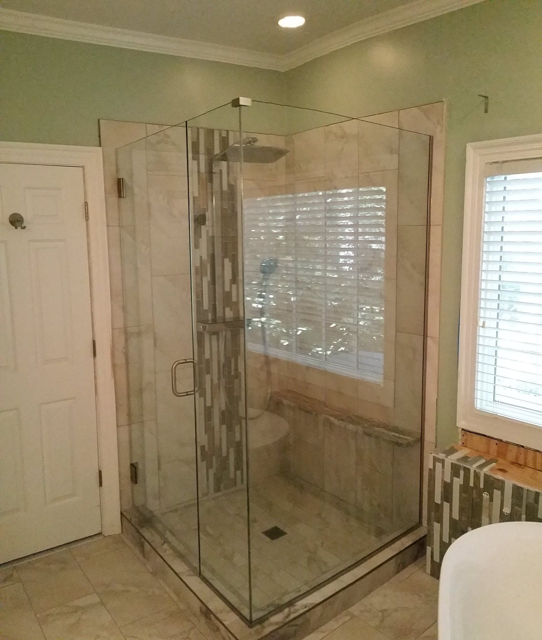 A bathroom with a walk in shower and a window
