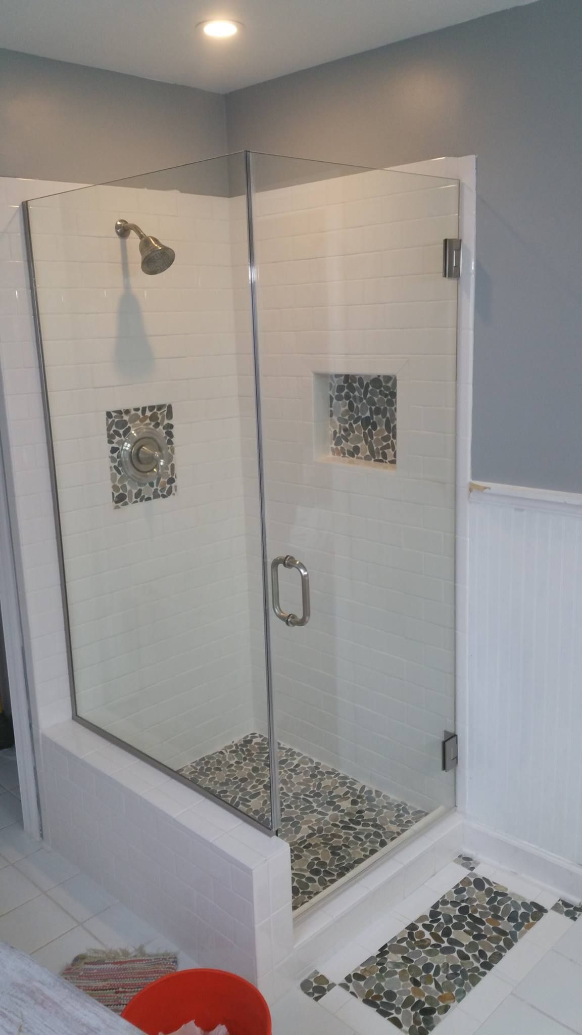 A bathroom with a walk in shower with a glass door