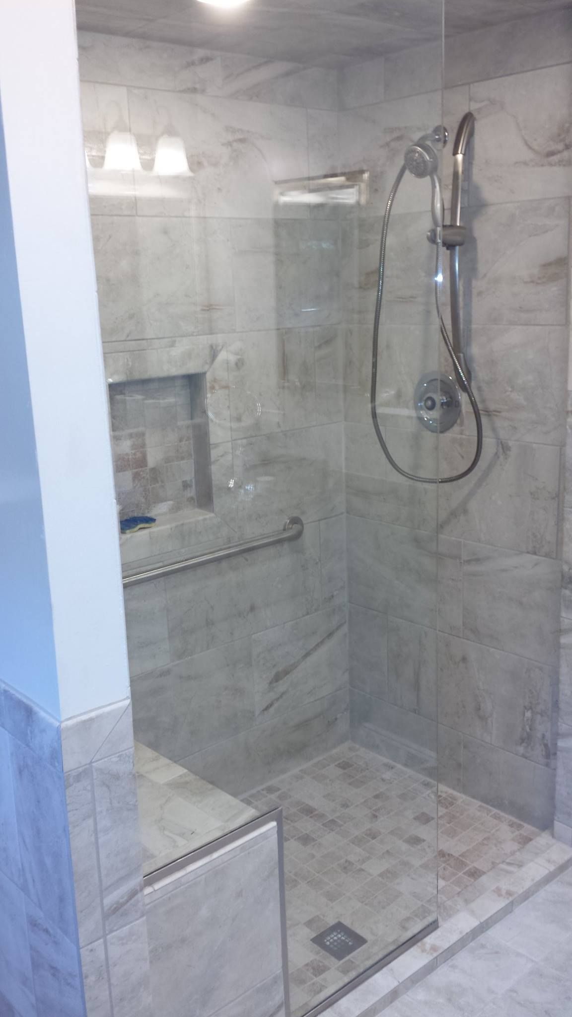 A bathroom with a walk in shower with a glass door and a shower head
