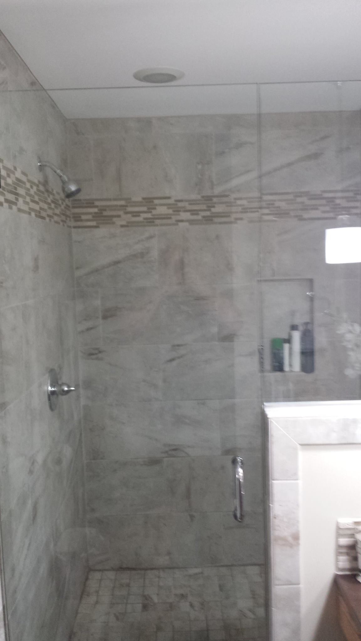 A bathroom with a walk in shower with a glass door
