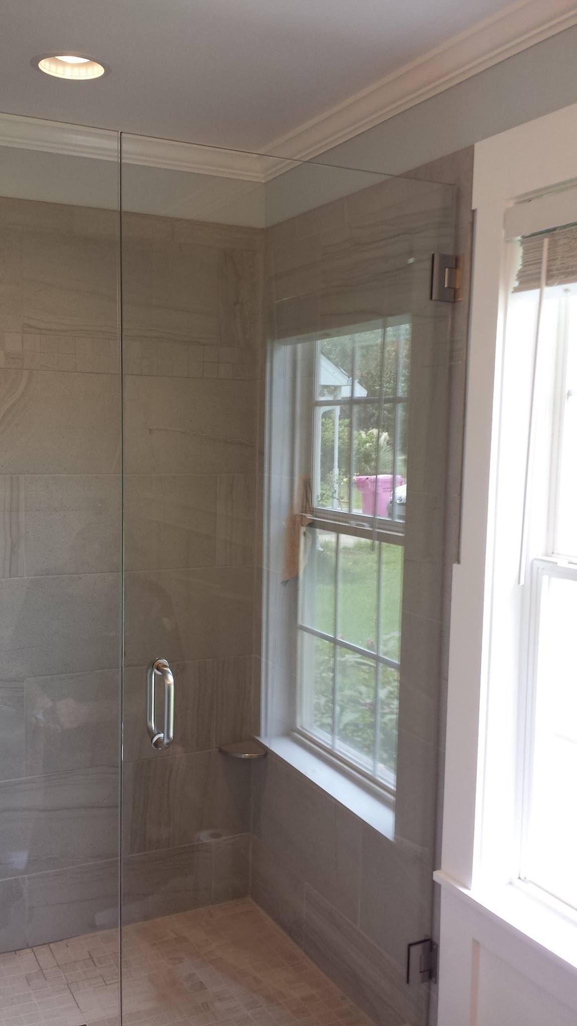 A bathroom with a walk in shower and a window