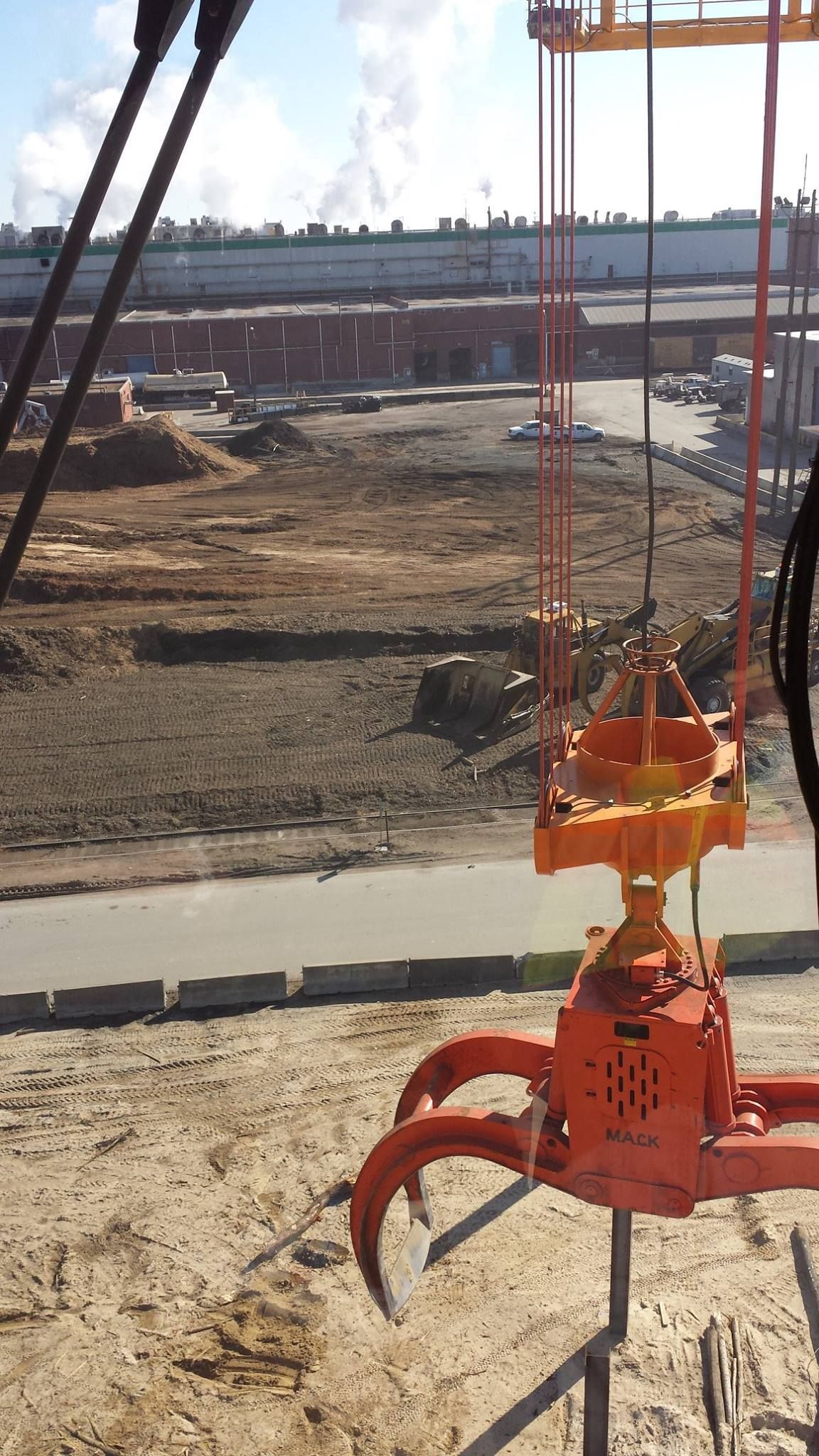 A large orange crane is sitting on top of a dirt field
