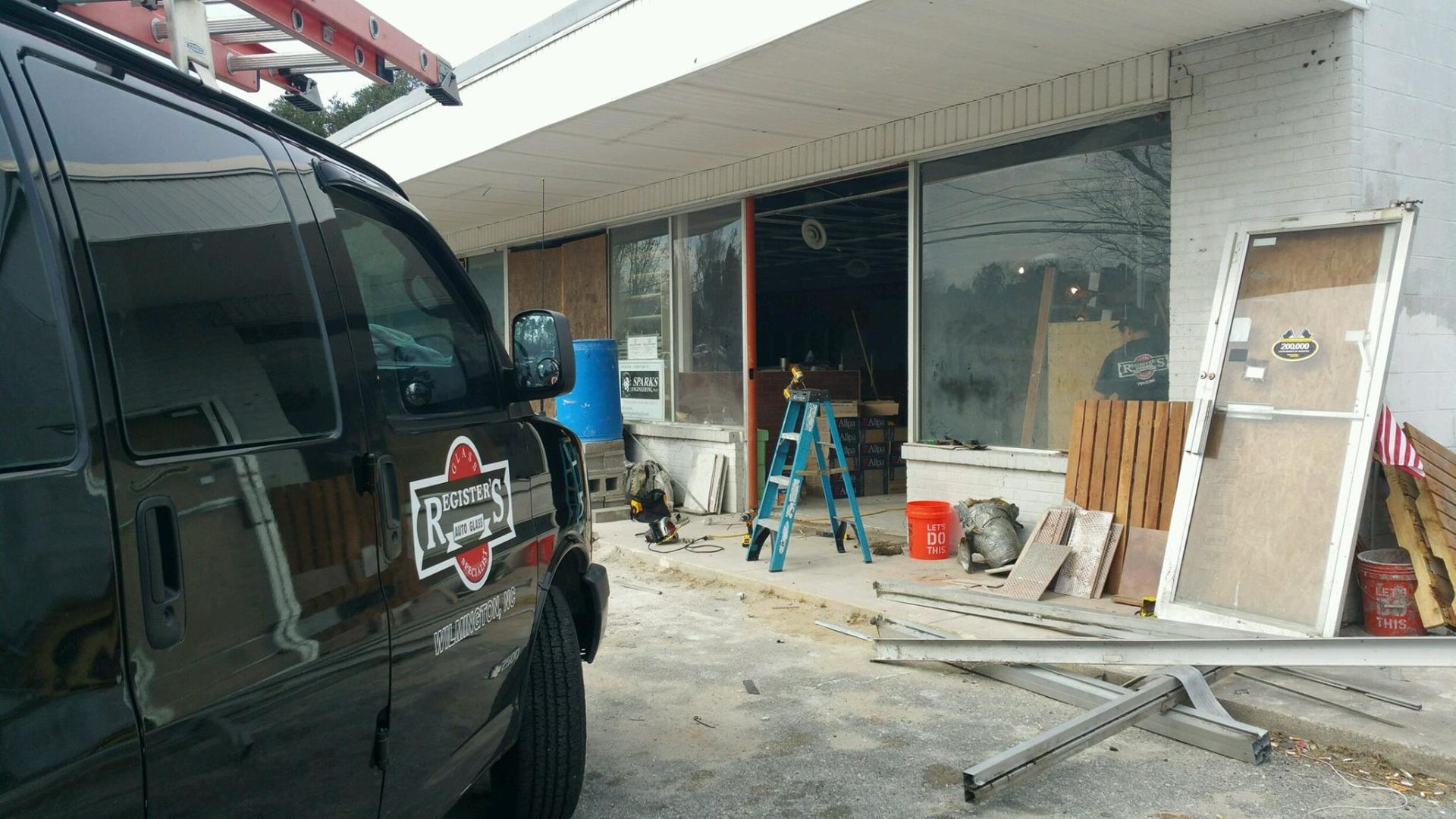 A black van is parked in front of a building under construction