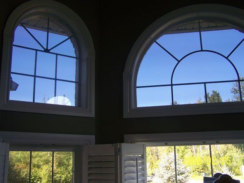 Two arched windows in a room with a blue sky behind them