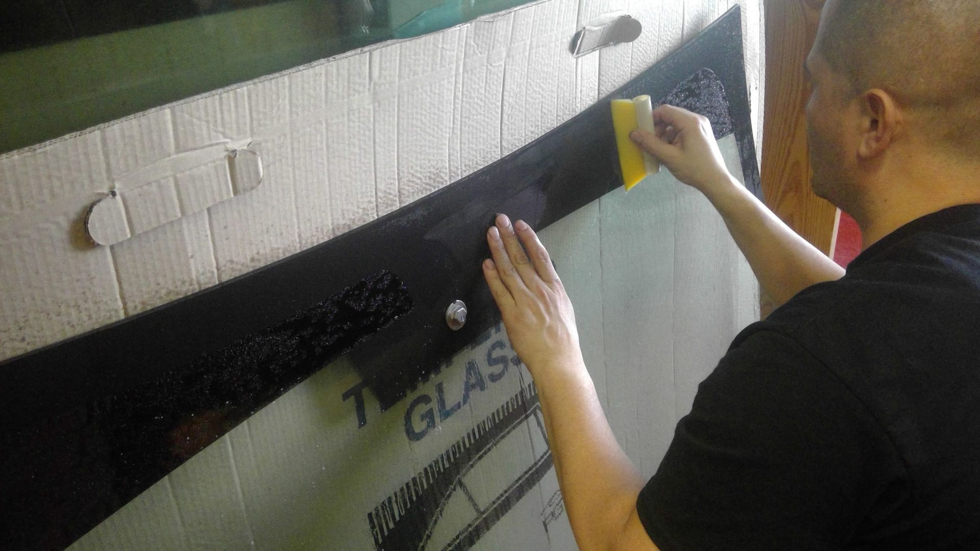 A man is cleaning a window with a yellow sponge