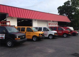 A row of vans are parked in front of a building with a red roof