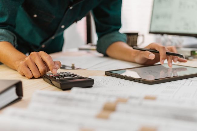 A man is using a calculator and a tablet at a desk.