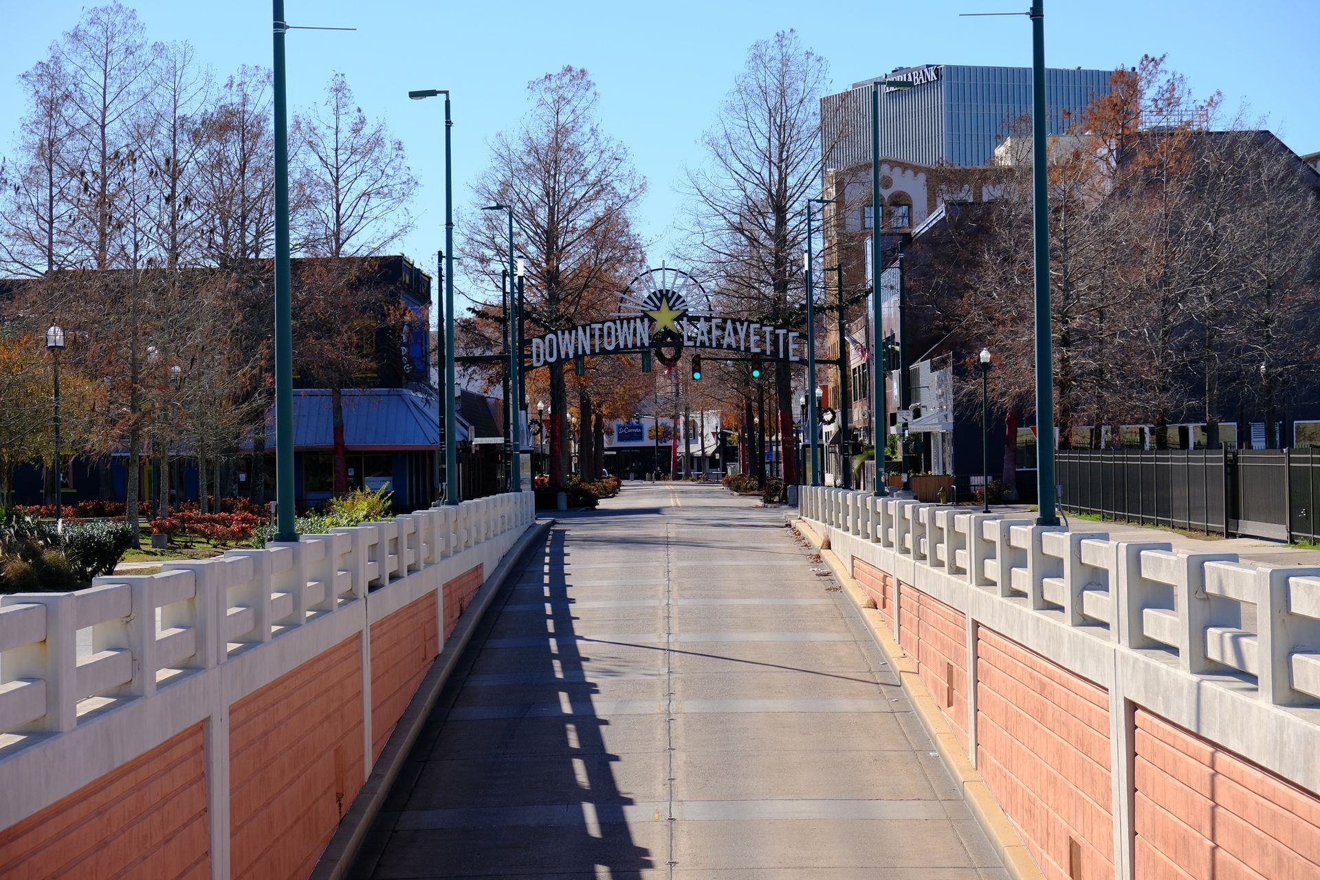 Brick bridge with decorative railings leading to an archway sign reading 