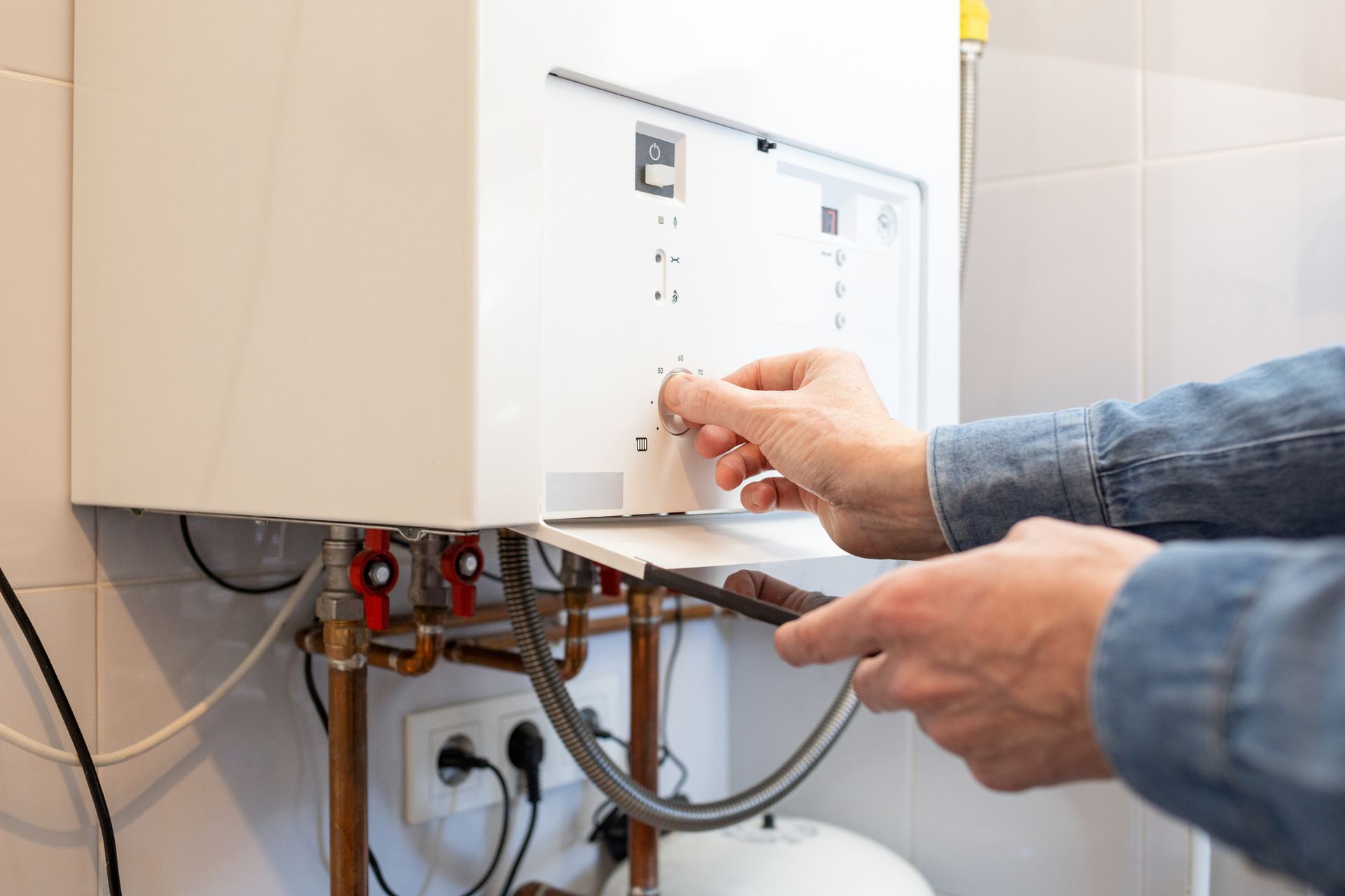 A white man lowers the temperature of the gas boiler in his house to save energy